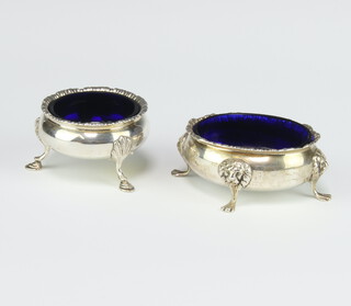 An Edwardian silver Georgian design salt with blue glass liner, lions mask and pad feet, a circular ditto on hoof feet London 1905 and 1908, 124 grams 