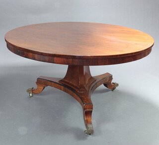A Regency circular rosewood snap top breakfast table raised on chamfered triform column and base ending in brass caps and casters, complete with bolts, 131cm diam.  