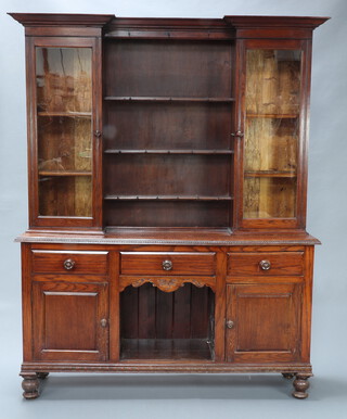 A late Victorian oak dog kennel dresser, the inverted breakfront upper section with moulded cornice, 3 shelves enclosed by glazed panelled doors flanked by cupboards, the base with 3 drawers above dog kennel recess flanked by panelled doors, raised on bun feet  207cm h x 161cm w x 41cm d 