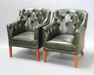 A pair of Georgian style club armchairs upholstered in green buttoned leather raised on square tapered supports, 84cm h x 67cm w x 57cm d (seats 31cm x 35cm) 