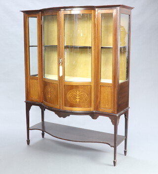 An Edwardian inlaid mahogany bow front display cabinet, upper section fitted cupboards enclosed by panelled doors, the base with undertier, raised on square tapered supports ending in bun feet 160cm h x 130cm w x 50cm d