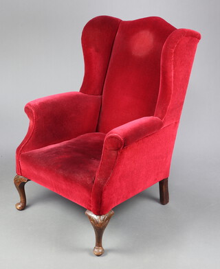 A Georgian style winged armchair upholstered in red material, raised on cabriole supports 105cm h x 74cm w x 69cm d (28cm x 40cm) 