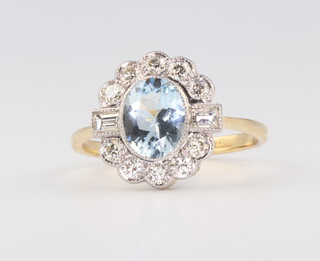A yellow metal, stamped 18ct, oval aquamarine and diamond ring, the centre stone 1.2ct, the brilliant cut diamonds 0.55ct, size O, 3.3gms