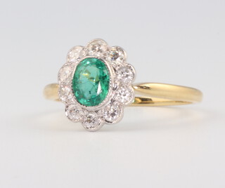 A yellow metal, stamped 18ct, oval emerald and diamond ring, the centre stone 0.6ct, the brilliant cut diamonds 0.4ct, size N 1/2