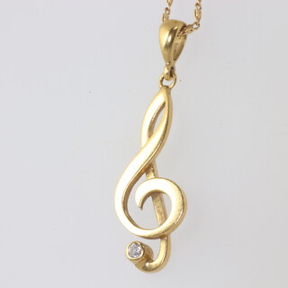 An 18ct yellow gold diamond set musical note pendant on an 18ct chain, 5.8gms