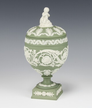A Wedgwood green Jasperware ovoid vase and cover with seated boy finial, the body decorated with scrolling flowers on a square base 22cm 