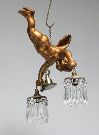 A gilt plaster painted light fitting in the form of a flying cherub holding 2 circular lozenge drops 33cm h x 25cm w 
