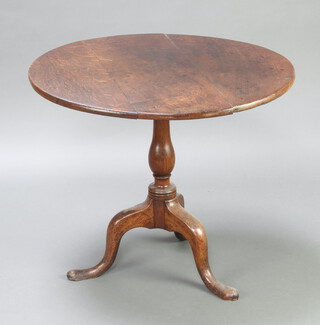 An 18th Century circular oak snap top tea table raised on a turned column and tripod base 67cm h x 79cm diam. 