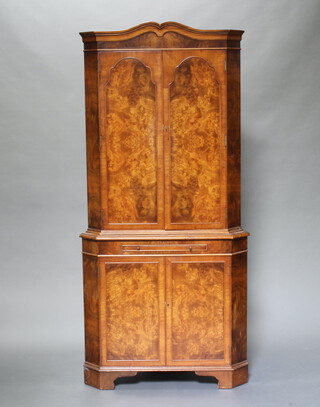 A Queen Anne style figured walnut double corner cocktail cabinet with shaped cornice, the upper section fitted shelves enclosed by arched panelled doors above brushing slide, the base enclosed by panelled doors, raised on bracket feet 187cm x 90cm w x 54cm d 