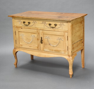 A 19th Century Louis style pine washstand fitted a drawer above cupboard enclosed by a pair of panelled doors, raised on cabriole supports with brass swan neck drop handles and swag decoration 72cm h x 92cm w x 47cm d 