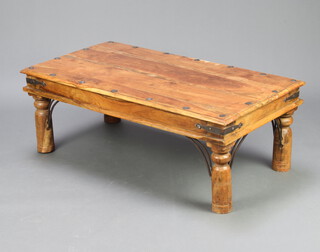 A rectangular Indian hardwood and studded coffee table raised on turned supports 40cm h x 110cm w x 61cm d 