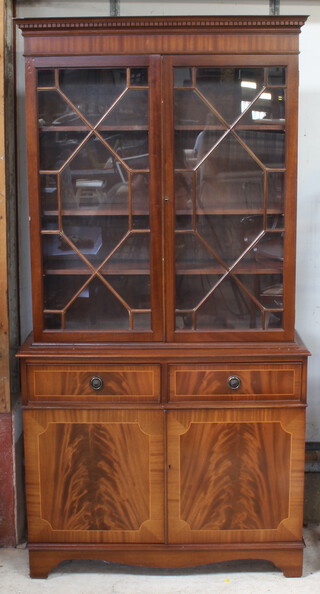 A Georgian style mahogany finished bookcase on cabinet with moulded and dentil cornice, fitted shelves enclosed by astragal glazed panelled doors, the base with 2 drawers above double cupboard enclosed by panelled doors, raised on bracket feet 193cm h x 99cm w x 36cm d (some contact marks) 