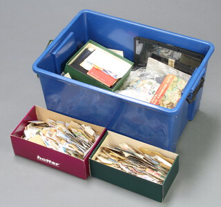 A collection of loose world stamps, some on paper, contained in a blue plastic crate
