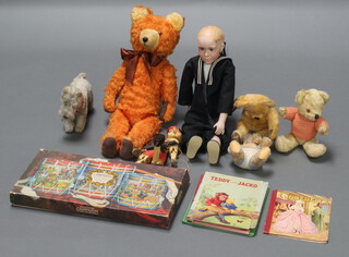 An orange teddy bear, 3 other bears, a cuddly dog, puppet and a doll sailor boy 