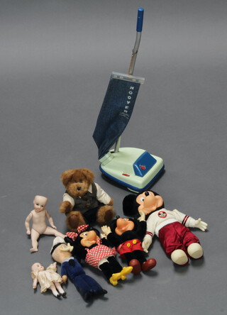 A child's toy Hoover upright vacuum cleaner, 2 Mickey Mouse figures, a Minnie Mouse figure, 2 small porcelain headed dolls and a small teddy bear contained in a black plastic box  