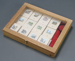 A pine table top display cabinet with hinged lid 9cm h x 56cm w x 43cm d, containing approximately 77 miniature prints 