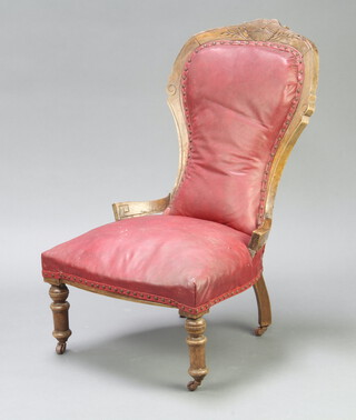A Victorian carved walnut show frame nursing chair upholstered in red material, raised on turned supports 88cm h  (frame is loose and signs of old but treated worm) 