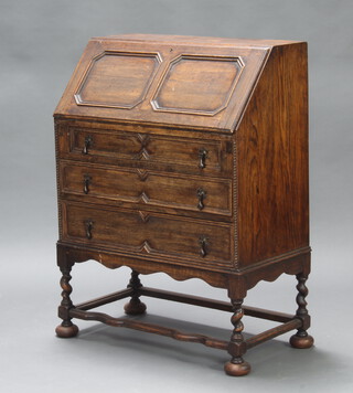 A 1930's oak Jacobean style bureau with fall front above 3 drawers, raised turned supports with shaped stretcher and bun feet 99cm h x 73cm w x 40cm d 
