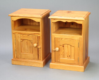 A pair of pine bedside cabinets fitted a recess above cupboard enclosed by a panelled door, raised on a platform base 67cm h x 45cm w x 38cm d (contact marks, light scratches)