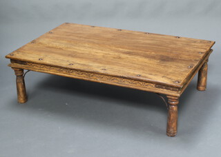 A rectangular Indian carved hardwood and studded coffee table raised on turned supports 40cm h x 137cm w x 91cm d 