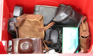 A red plastic crate containing a collection of various cameras 