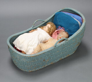 A blue wicker crib 43cm h x 83cm w x 46cm d containing 2 dolls 