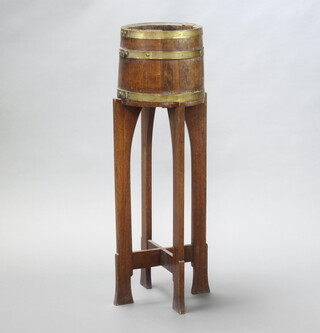 An Art Nouveau coopered oak and brass jardiniere stand raised on shaped supports with X framed stretcher 101cm h x 29cm diam. (some studs missing, frame is loose)