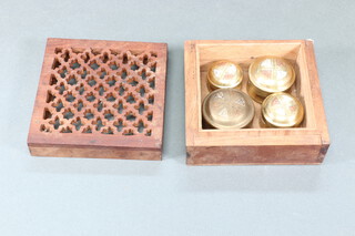 Four brass circular boxes contained in a pierced hardwood box 