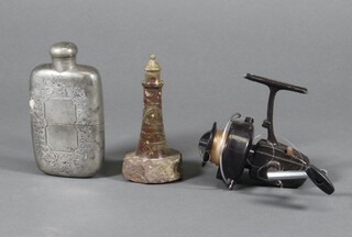 An Edwardian engraved pewter hip flask with cup base, a hardstone model of a lighthouse together with a plastic fishing reel 
