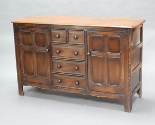 An Ercol elm sideboard comprising 2 short and 3 long drawers flanked by cupboard doors with turned wood handles 90cm h x 145cm w x 49cm d (water stains to the top) 