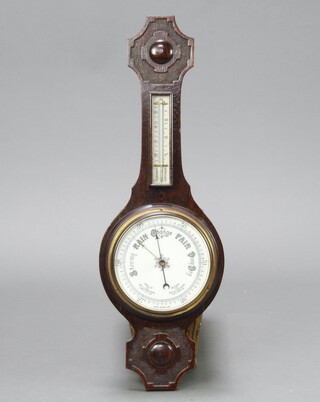 A 1930's aneroid barometer and thermometer with porcelain dial contained in a carved wheel case 77cm h x 26cm 
