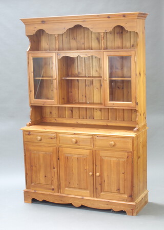 Greenwood Interiors Ltd., a Victorian style pine dresser, the raised back with moulded cornice, fitted a shelf above recess flanked by a pair of cupboards enclosed by glazed panelled doors above a recess, the base fitted 3 drawers above triple cupboards, raised on a platform base 87cm h x 135cm w x 46cm d (water stains to the top, handle missing to bottom right hand door) 