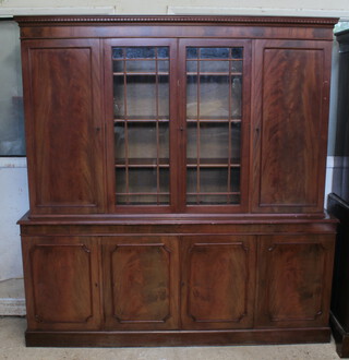 A Georgian style mahogany display cabinet on cabinet the upper section with moulded and dentilled cornice, the centre fitted shelves enclosed by astragal glazed panelled doors flanked by glazed panelled doors, the base enclosed by panelled doors, raised on  a platform base 189cm h x 174cm w x 38cm d (contact marks and light scratches in places) 