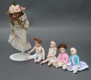 Five Victorian style porcelain headed dolls contained in a plastic box 
