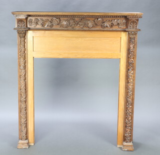 A Victorian oak fire surround with carved vinous decoration and turned columns to the sides 142cm h x 130cm w x 29cm d  