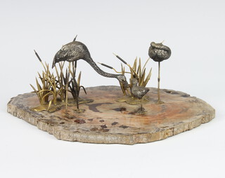 A group of white metal and gilt metal flamingos on a fossilised wood base 23cm 