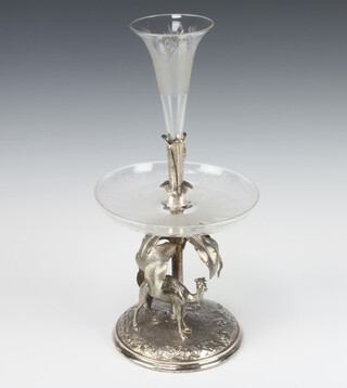 A Victorian repousse silver plated table centrepiece with a camel beneath a palm tree having a glass shallow dish etched with flowers with a raised banana leaf stem and a conical etched floral trumpet vase 40cm 