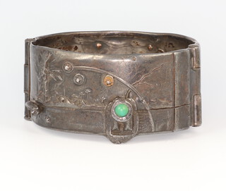 Gisela Seibert-Philippen, a stylish grey metal repousse bracelet decorated with a pig, a bull, trees and a figure set with a brilliant cut diamond, a cabochon cut jade and yellow metal stud work, inscribed Seibert 1976, 
