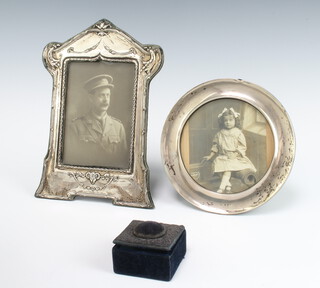 An Edwardian repousse silver photograph frame with swags and rams head Birmingham 
1907 23cm, a circular ditto 16cm, rubbed marks and a square mounted pin cushion 1905 5cm 