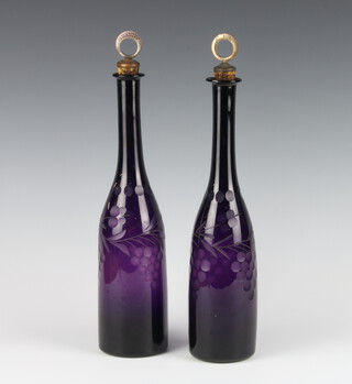 A pair of 19th Century amethyst cut glass bottles decorated with grapes with metal mounted stoppers, Gin and Brandy, 37cm