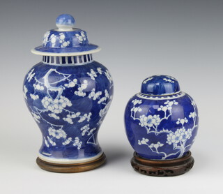 A blue and white prunus ginger jar and cover on wooden stand 15cm, a baluster ditto with lid and hardwood stand 25cm 