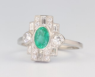 A white metal stamped Plat Edwardian style oval emerald and diamond ring, the centre stone 0.8ct, the brilliant cut diamonds 0.65ct, size P, 4 grams 