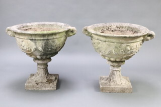A pair of well weathered twin handled concrete garden urns, raised on square bases (in 2 sections) 69cm h x 77cm x 65cm  