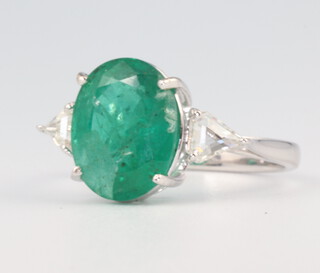 A white metal stamped 18K oval emerald 4.5ct and 2 triangular cut diamonds 0.43ct ring size M 1/2, 3.8 grams