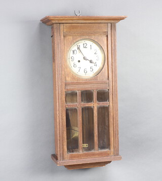 A 1920's 8 day striking wall clock with 15cm dial contained in an oak case 70cm h x 37cm w x 19cm d complete with pendulum and key 