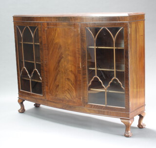 A 1930's Chippendale style mahogany bow front display cabinet, centre enclosed by a panelled door flanked by a pair of cupboards enclosed by astragal glazed panelled doors, raised on cabriole ball and claw supports 115cm h x 153cm w x 40cm d 