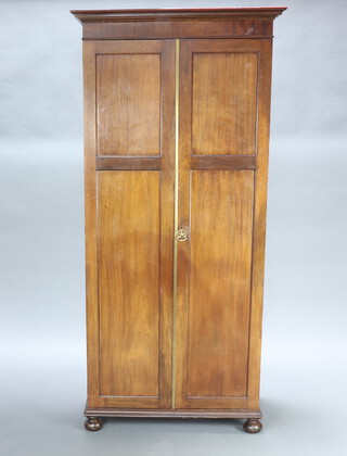 A Victorian mahogany wardrobe with moulded cornice enclosed by a panelled door, raised on bun feet 181cm h x 85cm w x 48cm d 