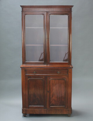 A Victorian mahogany D shaped cabinet on cabinet, the upper section with moulded cornice, fitted adjustable shelves enclosed by arched glazed panelled doors, the base fitted a drawer above double cupboard, raised on turned supports 214cm h x 99cm w x 45cm d 