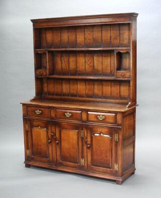 A 17th Century style oak dresser, the raised back with moulded cornice fitted shelves flanked by 2 short drawers, the base with 3 drawers above triple cupboards enclosed by arched panelled doors 187cm h x 138cm w x 45cm d 