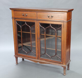 An Edwardian inlaid mahogany and crossbanded bookcase, the upper section fitted 2 drawers above cupboard with fitted shelves enclosed by astragal glazed panelled doors, raised on turned supports 113cm h x 112cm w x 30cm d 